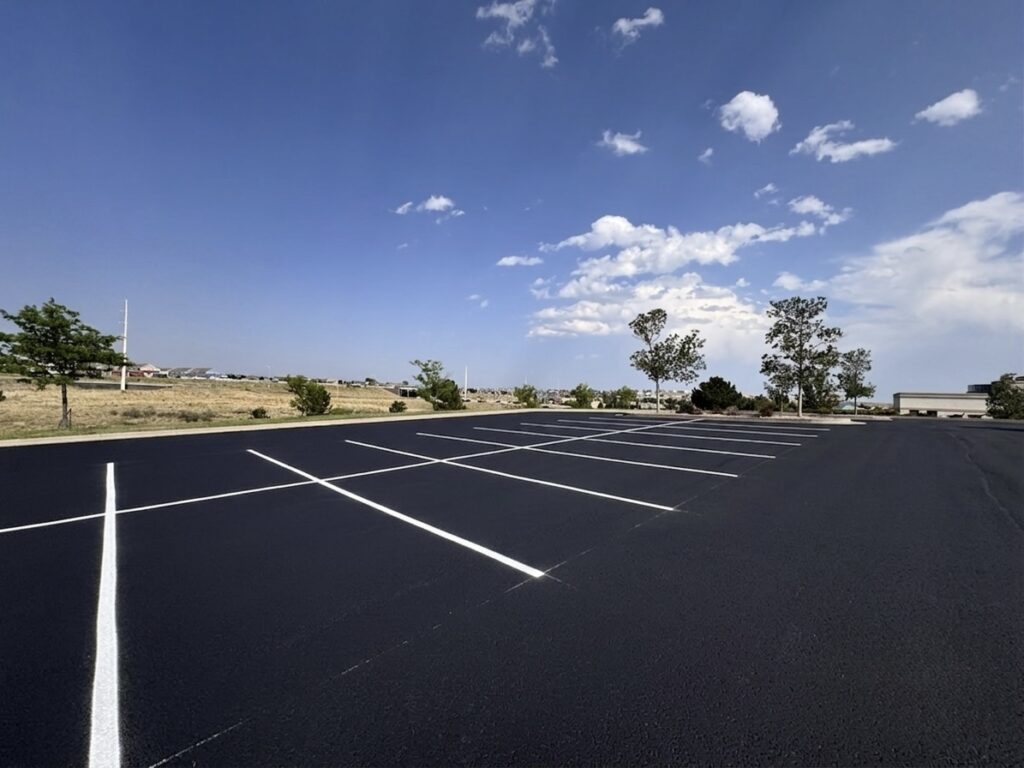 Wide view of a freshly sealcoated parking lot with crisp white parking stall lines
