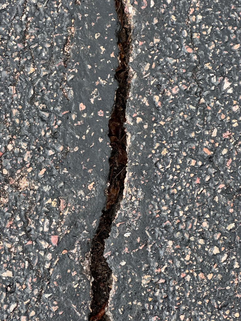 Close-up of an open asphalt crack in a parking lot before hot-pour crack sealing