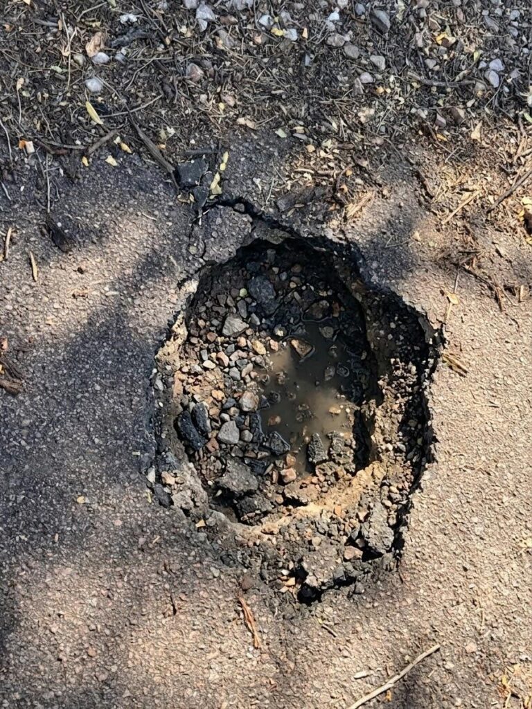 Water-filled pothole in an asphalt parking lot that needs repair