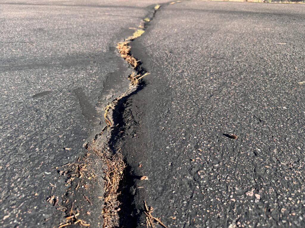 Long open crack running across an asphalt parking lot before crack sealing